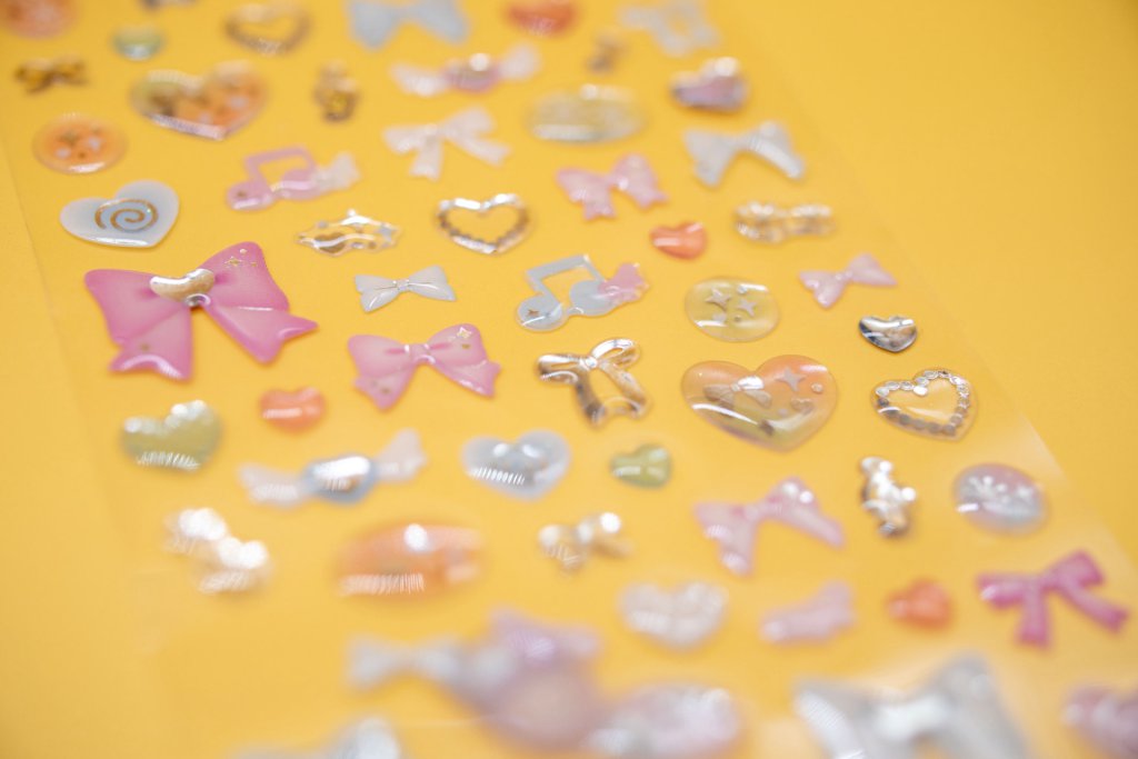 Bow, star and heart-shaped domed stickers on a sample sheet