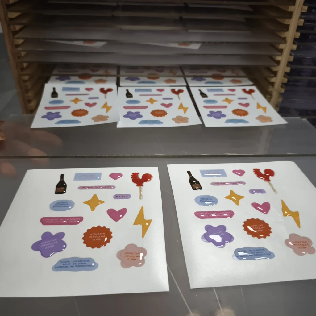 Temperature, Humidity, and Cure Time in Resin Doming Domed sticker sheets supported horizontally on trays in a curing rack