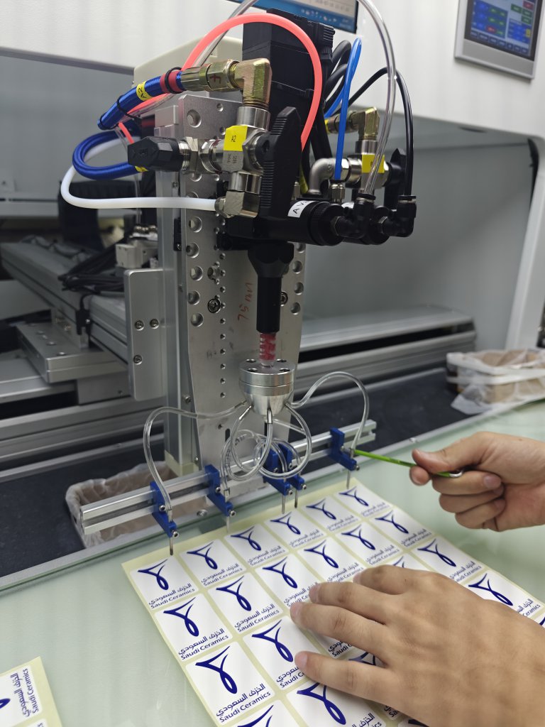 SJ4060 multi-needle dispensing module above a sheet of identical logo labels