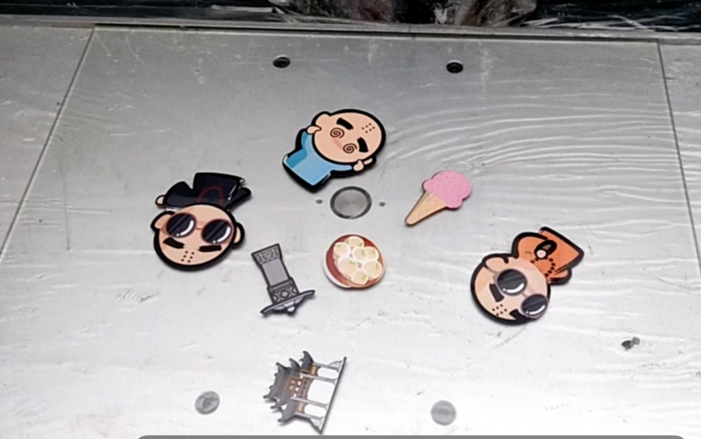 Seven cartoon fridge magnets in different shapes and sizes on the SJ4060 worktable